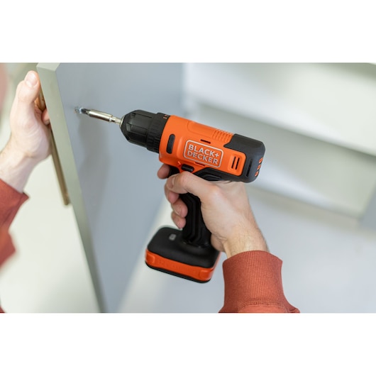 BLACK+DECKER cordless drill BCD712VHD used to assemble furniture, close-up of tool in hand.