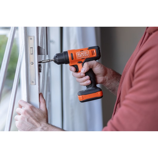 Photo of BLACK+DECKER BCD712VHD cordless drill being used to install hardware on a white window frame.