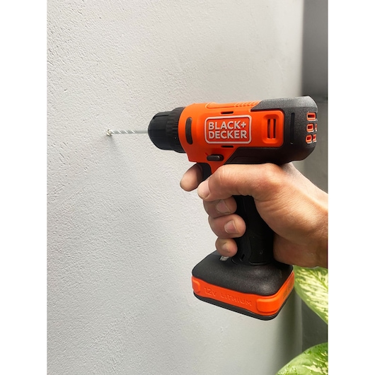 Photo of BLACK+DECKER BCD712VHD cordless orange and black drill with 12V lithium battery being used to drill into a wall.