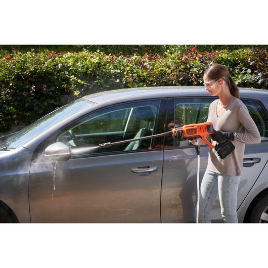 BLACKDECKER BCPC20D1 portable pressure washer used to clean a car outdoors.