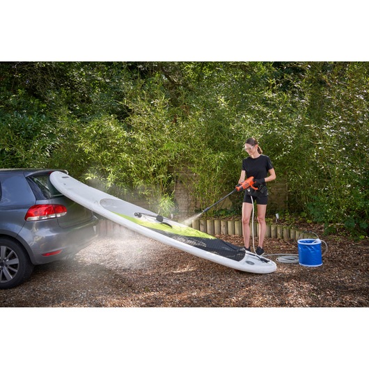 BLACK+DECKER BCPC20D1 portable pressure washer cleaning paddleboard outdoors, product in use.