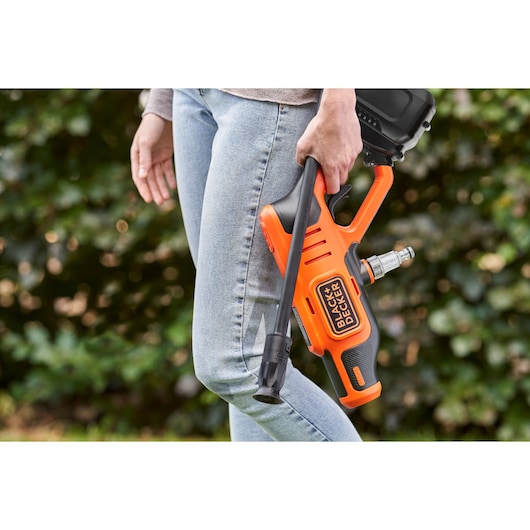 BLACKDECKER BCPC20D1 portable power washer held by person outdoors, orange and black design.