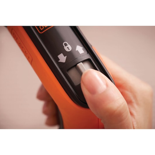Close-up photo of a hand using the BLACKDECKER BCRTA601I tool slider switch with lock and directional arrows.