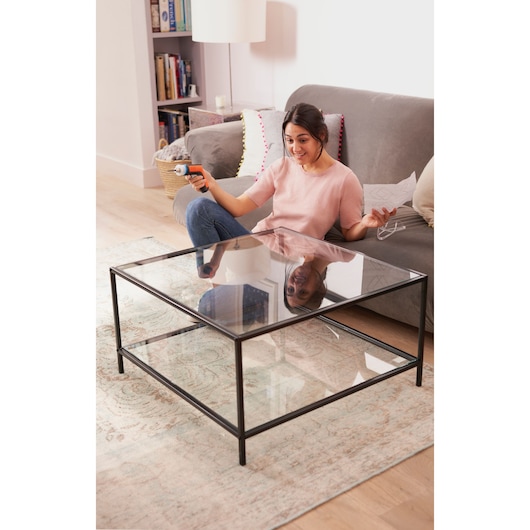 BLACKDECKER BCRTA601I electric screwdriver held by person assembling glass coffee table in living room