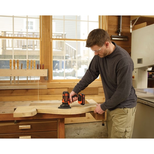 Photo of person using BLACKDECKER BDCDM6KITC cordless power tool on wood in workshop.