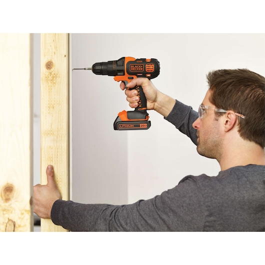 Photo of BLACKDECKER cordless drill BDCDM6KITC, orange and black, used to drill a screw into a wooden frame.