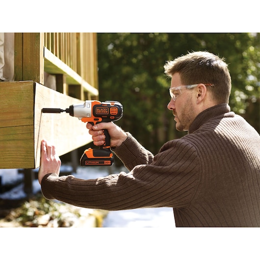 BLACKDECKER BDCDM6KITC cordless drill in use outdoors on wooden structure.