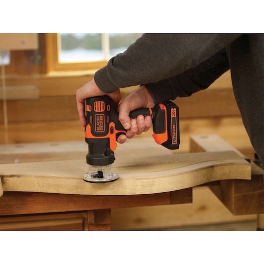 Photo of BLACK+DECKER BDCDM6KITC cordless 20V lithium router in use on a wooden board indoors.