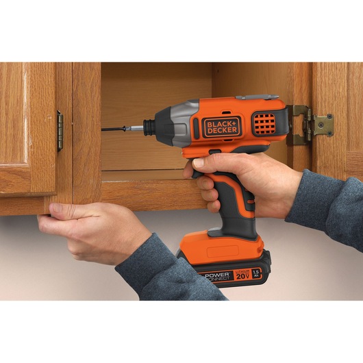 Photo of BLACK+DECKER BDCI20C cordless impact driver in use assembling a wooden cabinet.