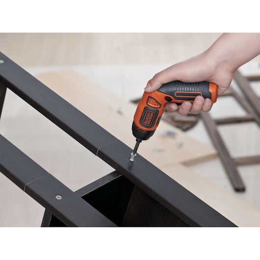 Photo of BLACKDECKER BDCS36F cordless screwdriver being used to assemble dark wooden furniture.