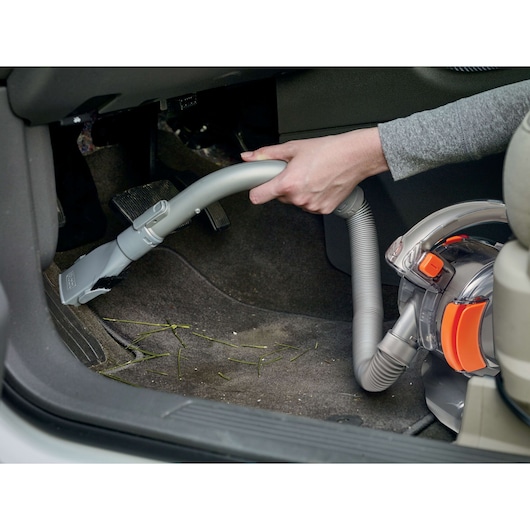 BLACK+DECKER BDCV560F-LA vacuum cleaner used to clean car floor mat with hose and brush attachment.