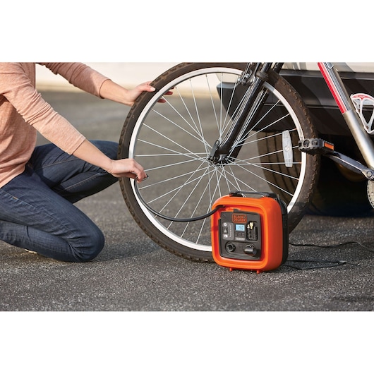 BLACKDECKER BDINF12 portable inflator used to inflate a bicycle tire outdoors