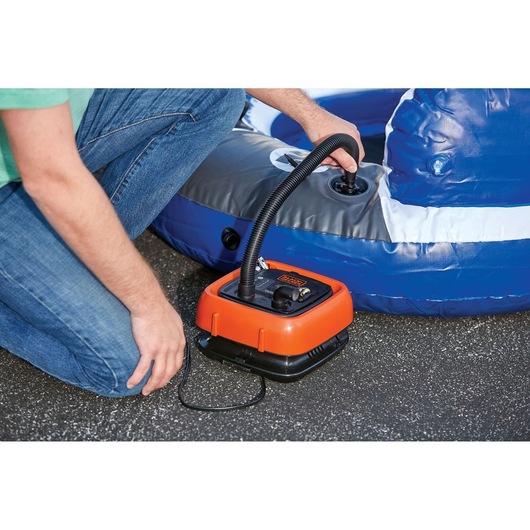 BLACKDECKER BDINF12 orange inflator pumping air into a blue inflatable on asphalt, close-up.