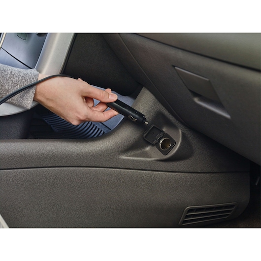 BLACKDECKER BDINF12 car inflator plug being inserted into vehicle power outlet, close-up angle.