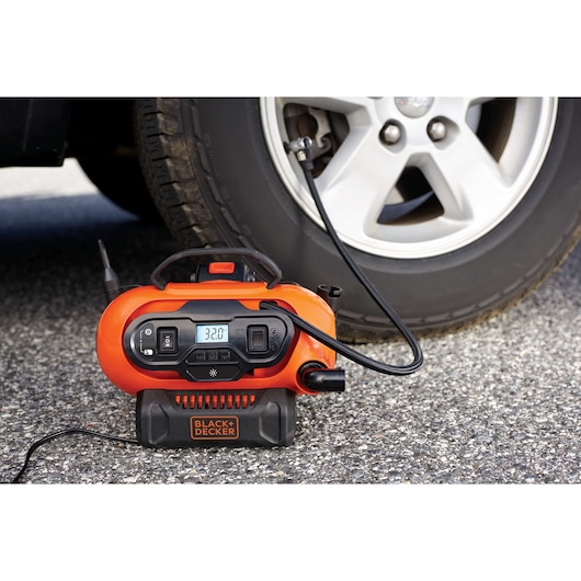 BLACKDECKER BDINF20 orange digital tire inflator in use with a car tire, photography outdoors.