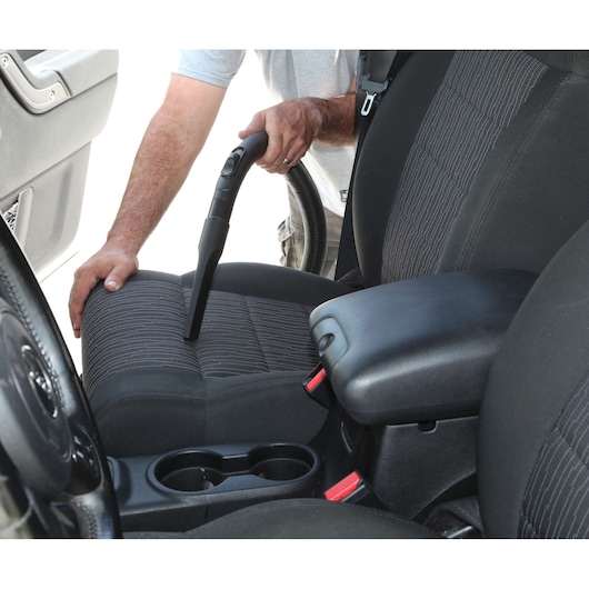BLACKDECKER BDWDS20 handheld vacuum being used to clean car seat upholstery, side angle.