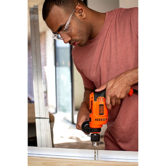 BLACKDECKER BED713650 corded drill used for woodworking, bright orange housing, handheld, indoor setting.