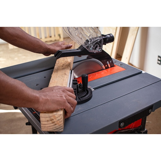 BLACKDECKER BES71800TSS table saw cutting wood, hands guiding board, close-up angle.