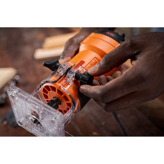 Photo of BLACKDECKER BETR0500 compact wood router being adjusted by hand on a wooden workbench.