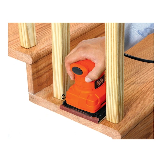 BLACKDECKER BS200 orange hand sander sanding wooden staircase, close up view.