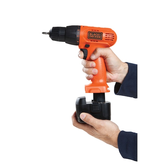 BLACKDECKER CD121K cordless drill with orange body, black battery, held by two hands, side angle.