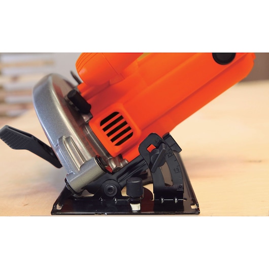 BLACKDECKER CS1004 circular saw side angle showing orange body and bevel adjustment lever on wood surface.