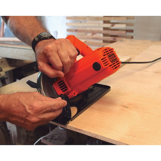 Photo of BLACKDECKER CS1004 circular saw in use, cutting light wood on workbench.