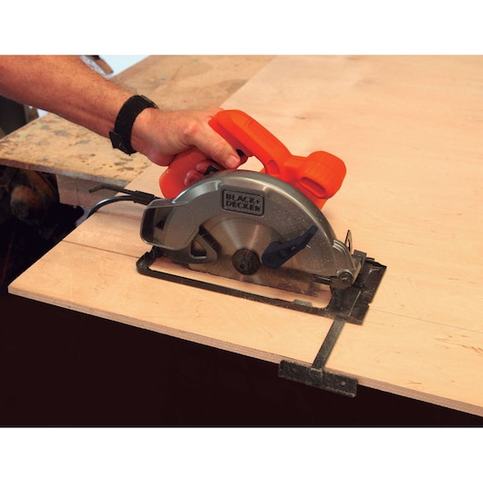 BLACK+DECKER CS1004 circular saw cutting light wood, side view, orange and gray housing visible.
