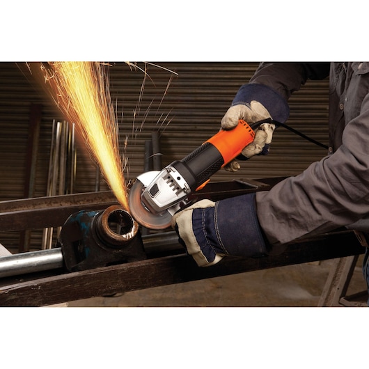 BLACKDECKER G720 angle grinder cutting metal pipe with sparks, operated by gloved hands in workshop.