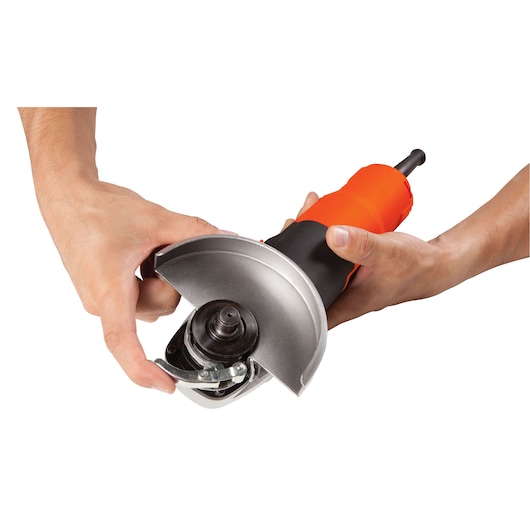 BLACKDECKER G720 angle grinder in orange and black, side view, being adjusted by hands.