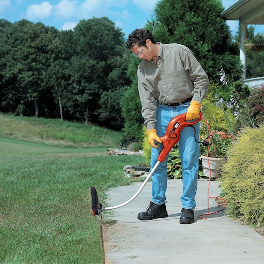 BLACKDECKER GH1100 string trimmer outdoor use, man trimming lawn edge with orange electric tool.