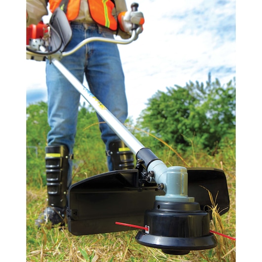 Photo of BLACKDECKER GST33 grass trimmer in use outdoors, close-up of cutting head and protective shield.