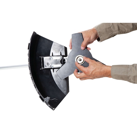 BLACK+DECKER GST43 brush cutter blade installation close-up, hands mounting blade, white background.
