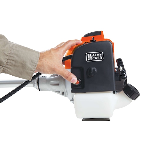 Photo of BLACKDECKER GST43 grass trimmer engine with a hand pressing the start button, white background.