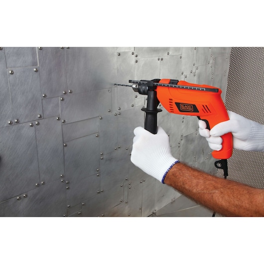 BLACKDECKER HD650 orange corded drill with side handle, in use drilling into metal surface.