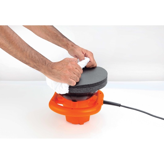 Photo of hands attaching a white cloth to BLACKDECKER KP12K orange buffer polisher, side angle on white background.