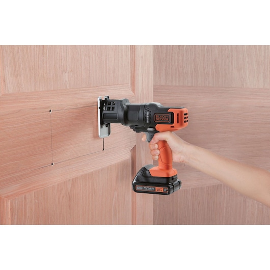 BLACKDECKER MTX20K6A cordless multi-tool used for cutting into a wooden door, side view.