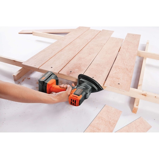 BLACKDECKER MTX20K6A cordless sander used on wooden boards, close-up angle.