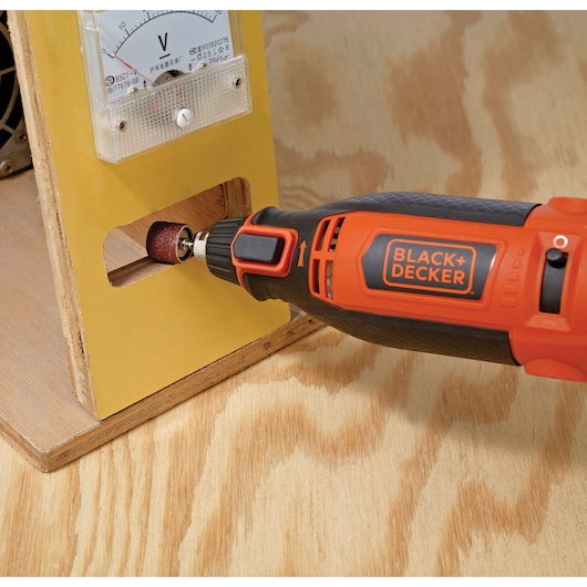 Photo of BLACKDECKER RT18KA rotary tool sanding wood, close-up side view.