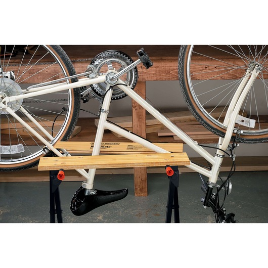 BLACKDECKER WM125 portable workbench holding a white bicycle upside down, indoor workshop setting, front angle.
