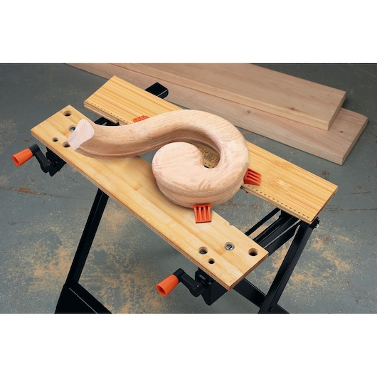 BLACKDECKER WM125 portable workbench with wooden spiral piece secured, front angle on white background.